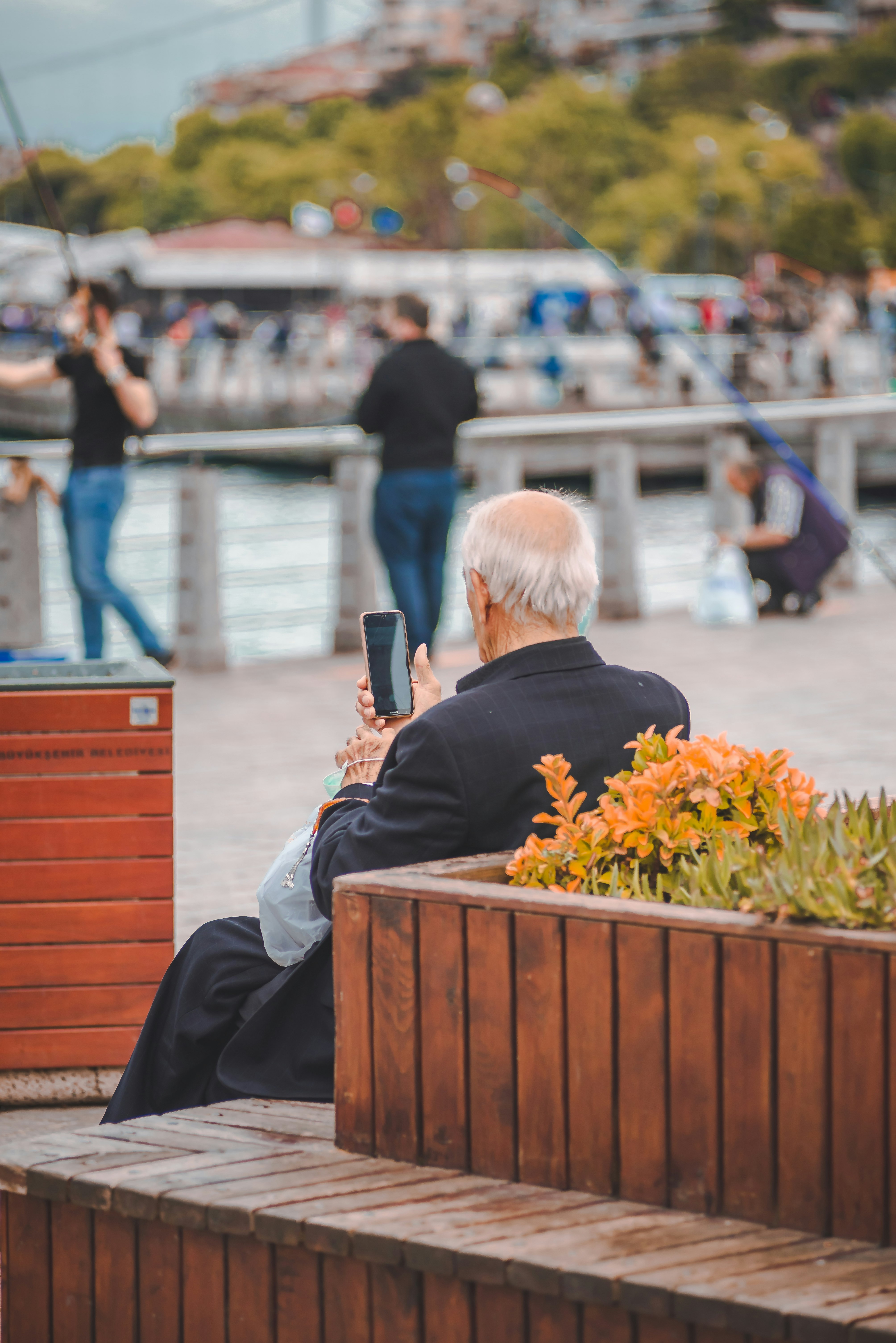 man in black suit sitting on brown wooden bench